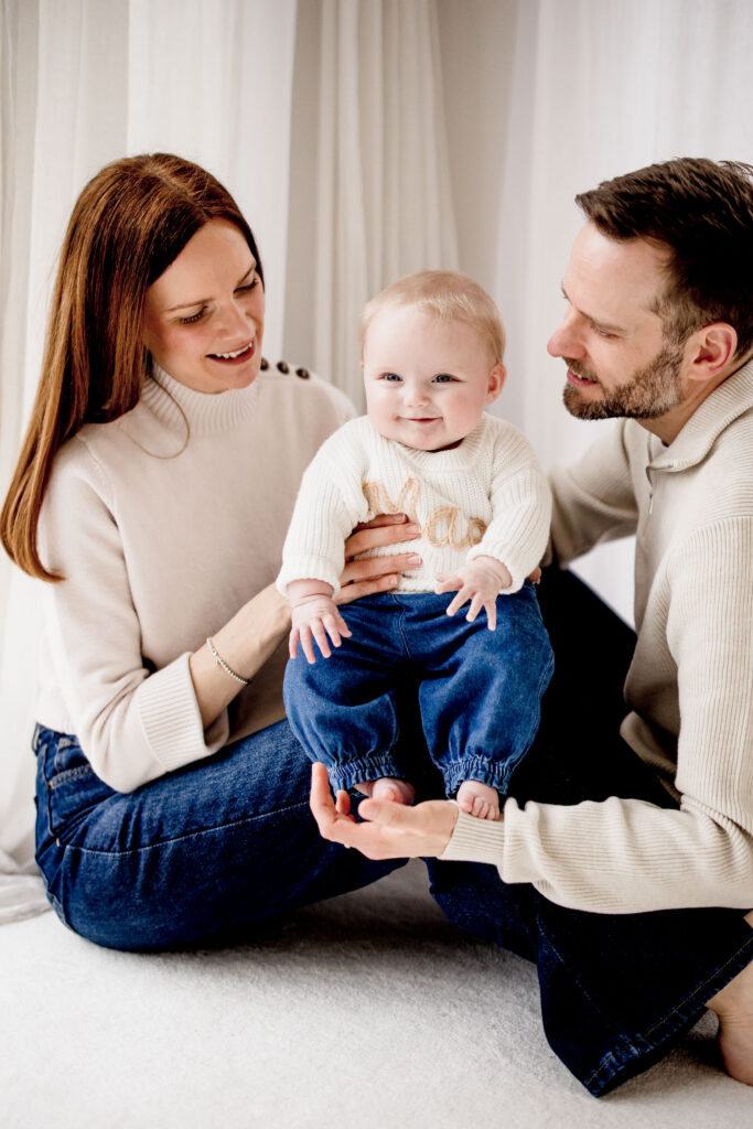 Mum and Dad with baby on photography session in a studio to celebrate 6 month milestone of the baby girl.